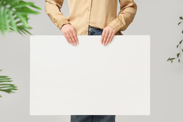 Young woman holding blank poster on white background