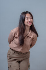 Portrait of a young Indonesian woman in casual brown outfit leaning slightly forward with a...