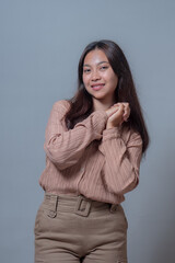 Young Indonesian woman with long hair posing in a studio, wearing a beige outfit and smiling...