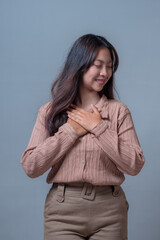 An Indonesian Asian woman smiling gently with her hands placed over her chest in a heartfelt...