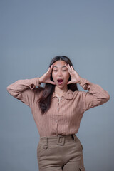 Indonesian woman in beige blouse and beige pants, expressing frustration or stress while holding...