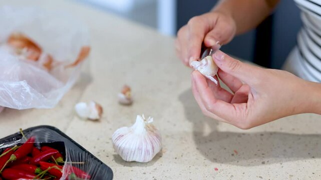 Hands Peeling Garlic in a Kitchen Setting