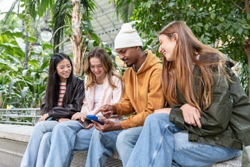 Group of diverse young friends sharing a phone moment outdoors