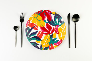 Top view of colorful plate, black cutlery on white background. Exotic plant plate, summer picnic. Flat lay, copy space.