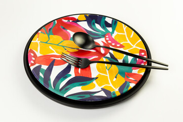 Top view of black tray, colorful plate, black cutlery on white background. Exotic plant plate, summer picnic. Flat lay, copy space.