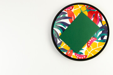 Top view of black tray, colorful plate, green card on white background. Exotic plant plate, summer picnic. Flat lay, copy space.