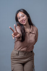 Cheerful Indonesian woman with long hair poses playfully, smiling while extending her hand forward...