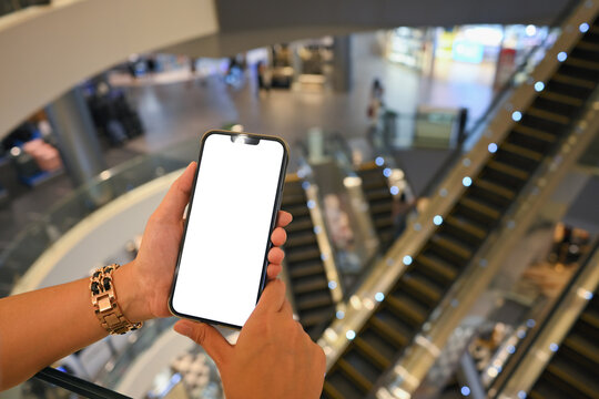Close up of female hands using smartphone with blank white screen in a modern shopping mall