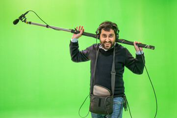 Boom microphone operator testing sound at TV studio on green key chroma background. High quality photo
