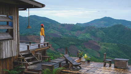 A woman standing on wooden terrace and looking at a mountain view