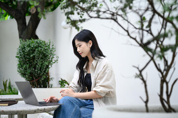 Freelancer enjoying remote work at a quiet outdoor cafe with green plants and natural light