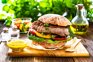 Takeaway sandwich with grilled beef steak and tomato served with fresh salad and vinaigrette sauce...