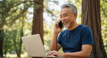 Senior Asian man with laptop in park, smiling and talking on phone outdoors – Remote work, digital communication and happiness concept.