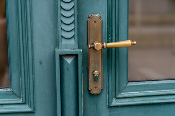 Vintage teal green color wooden door with ornate brass handle and keyhole