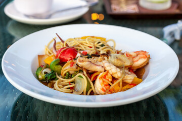 Spicy pasta with seafood. Vibrant seafood pasta spicy dish featuring shrimp, colorful vegetables and noodles, beautifully presented in white bowl, showcasing freshness and culinary artistry of meal