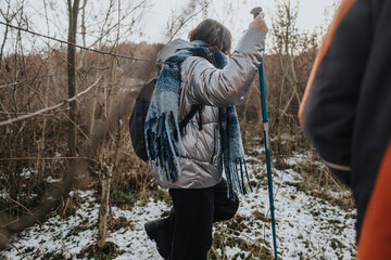 Two people hiking through a snow-dusted forest, enjoying the outdoors and engaging in winter...