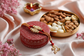 Fototapeta premium beautiful rakhi and box of dry fruits, and a puja thali with a single diya and flowers and sweets in thali