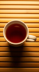 Photo of a steaming cup of dark tea rests on a textured wooden surface, offering a moment of warm relaxation and aromatic refreshment