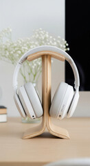 Photo of stylish white headphones rest elegantly on a natural wood stand, evoking a sense of modern audio enjoyment and focused listening