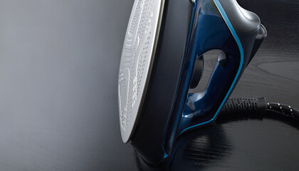 Steam iron resting vertically on a black wooden table