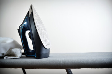 Clothes ironing concept with iron on ironing board isolated background