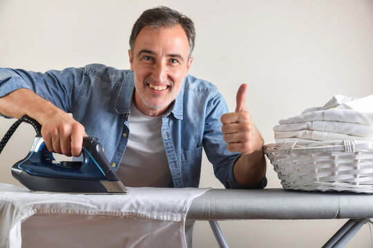 Man ironing shirt on an ironing board with ok gesture