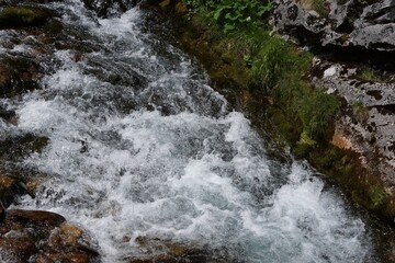 A turbulent mountain stream on a sunny day. Light can be seen reflecting off the water