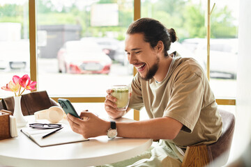 Young man enjoys remote work with matcha in a vibrant cafe during summer