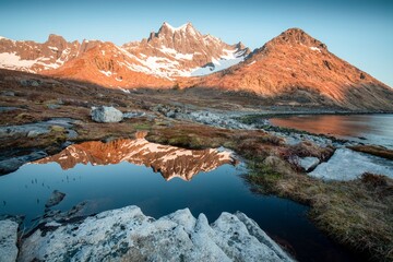 Scenery of blue waters and green mountains with remnants of snow in spring under clear skies on the island of Senja, Senja municipality, Troms county, Mefjorden,  Norway, Europe. Tourist area