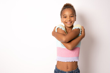 Pleased satisfied young African American girl hugging herself and smiling isolated over transparent...