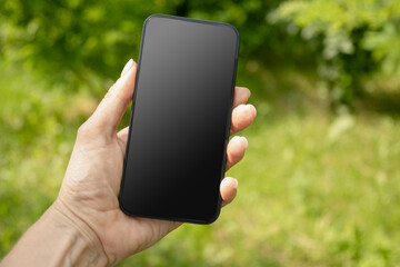 Close up of womans hands holding smartphone in outdoor green setting. Check apps, focused on device, chatting, performance data. Voice assistant. Fitness progress on app. Space for design on screen.