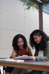 Two excited university students reviewing notes together at campus