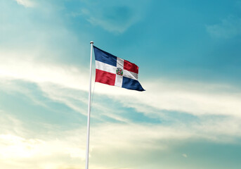 Dominican Republic flag is waving on a tall flagpole among the clouds. Dominican Republic national flag for independence day.