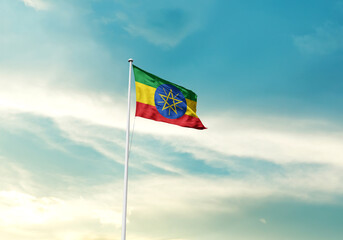 Ethiopia flag is waving on a tall flagpole among the clouds. Ethiopia national flag for independence day.