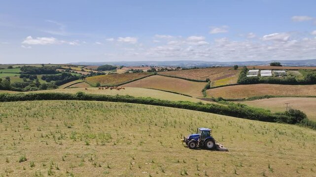 Farmer working with tractor in the fields of Devon from a drone, Torquay, England