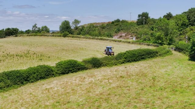 Farmer working with tractor in the fields of Devon from a drone, Torquay, England