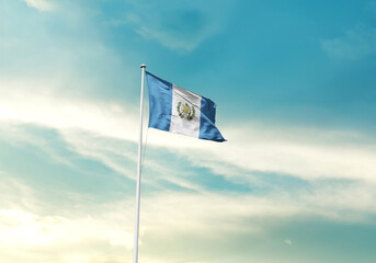 Guatemala flag is waving on a tall flagpole among the clouds. Guatemala national flag for independence day.