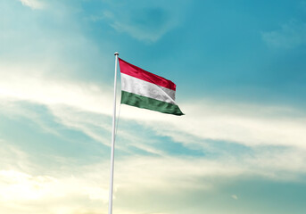 Hungary flag is waving on a tall flagpole among the clouds. Hungary national flag for independence day.