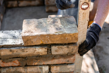 Close-up of leveling bricks during construction of brick structure using spirit level