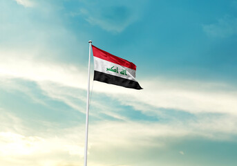 Iraq flag is waving on a tall flagpole among the clouds. Iraq national flag for independence day.