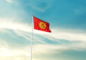 Kyrgyzstan flag is waving on a tall flagpole among the clouds. Kyrgyzstan national flag for independence day.