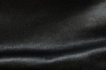 Background of black leather with folds and shadows close-up, leather bag