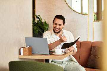 Young man enjoying remote work at a cozy cafe with laptop and coffee