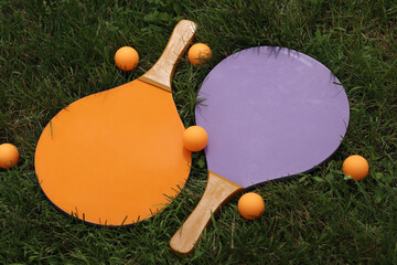 Wooden tennis rackets and balls on the grass. Beach tennis. Summer active recreation, games and sports. Play beach tennis in the park