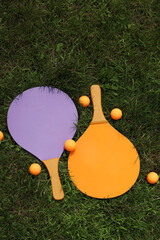 Wooden tennis rackets and balls on the grass. Beach tennis. Summer active recreation, games and sports. Play beach tennis in the park