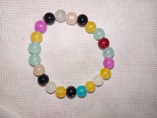 A colorful beaded bracelet with vibrant round beads in yellow, white, blue, black, and purple is...