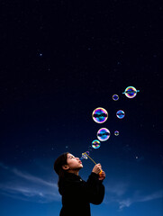 Man blowing cosmic bubbles into starry universe sky