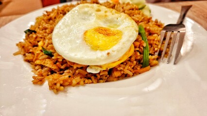 Traditional fried rice with authentic Indonesian spices served on a white plate. A mix of tropical spices and vegetables.