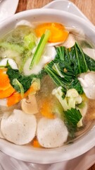 A capcay dish served in a white bowl with various vegetables and meats and a soup typical of Indonesian cuisine.