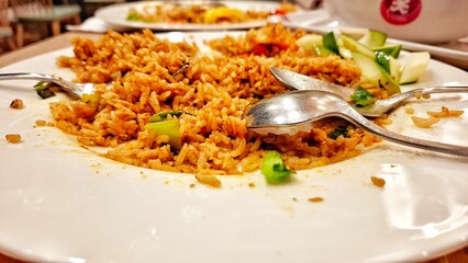 Traditional fried rice with authentic Indonesian spices served on a white plate. A mix of tropical spices and vegetables.